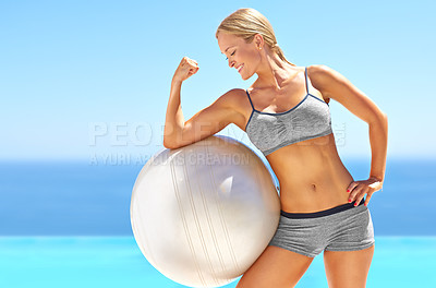 Buy stock photo Shot of an attractive young woman flexing her bicep on an exercise ball