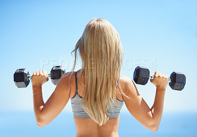 Buy stock photo Rearview shot of young woman exercising with dumbbells outside