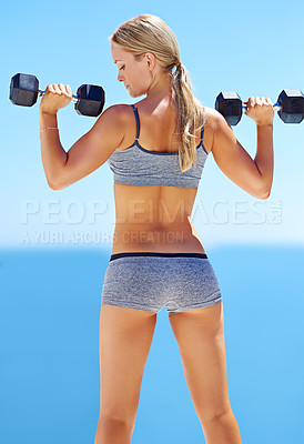 Buy stock photo Rearview shot of young woman exercising with dumbbells outside