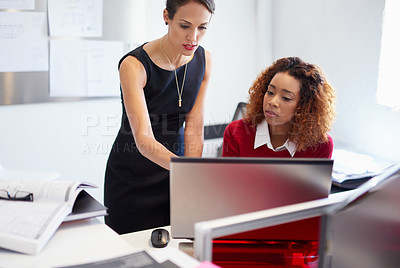 Buy stock photo Shot of two attractive designers at work on a computer in the office