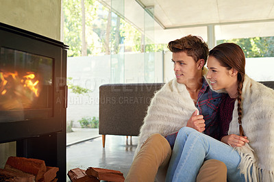 Buy stock photo Shot of an affectionate couple sitting by the fireplace in their living room