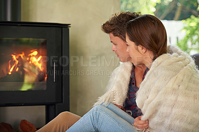 Buy stock photo Shot of an affectionate couple sitting by the fireplace in their living room