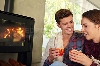 Buy stock photo Shot of a young couple drinking hot chocolate by the fireplace
