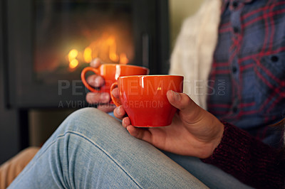 Buy stock photo Cropped shot of a young couple drinking hot chocolate by the fireplace