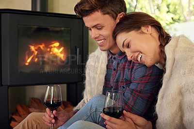 Buy stock photo Shot of an affectionate couple drinking a glass of wine by the fireplace