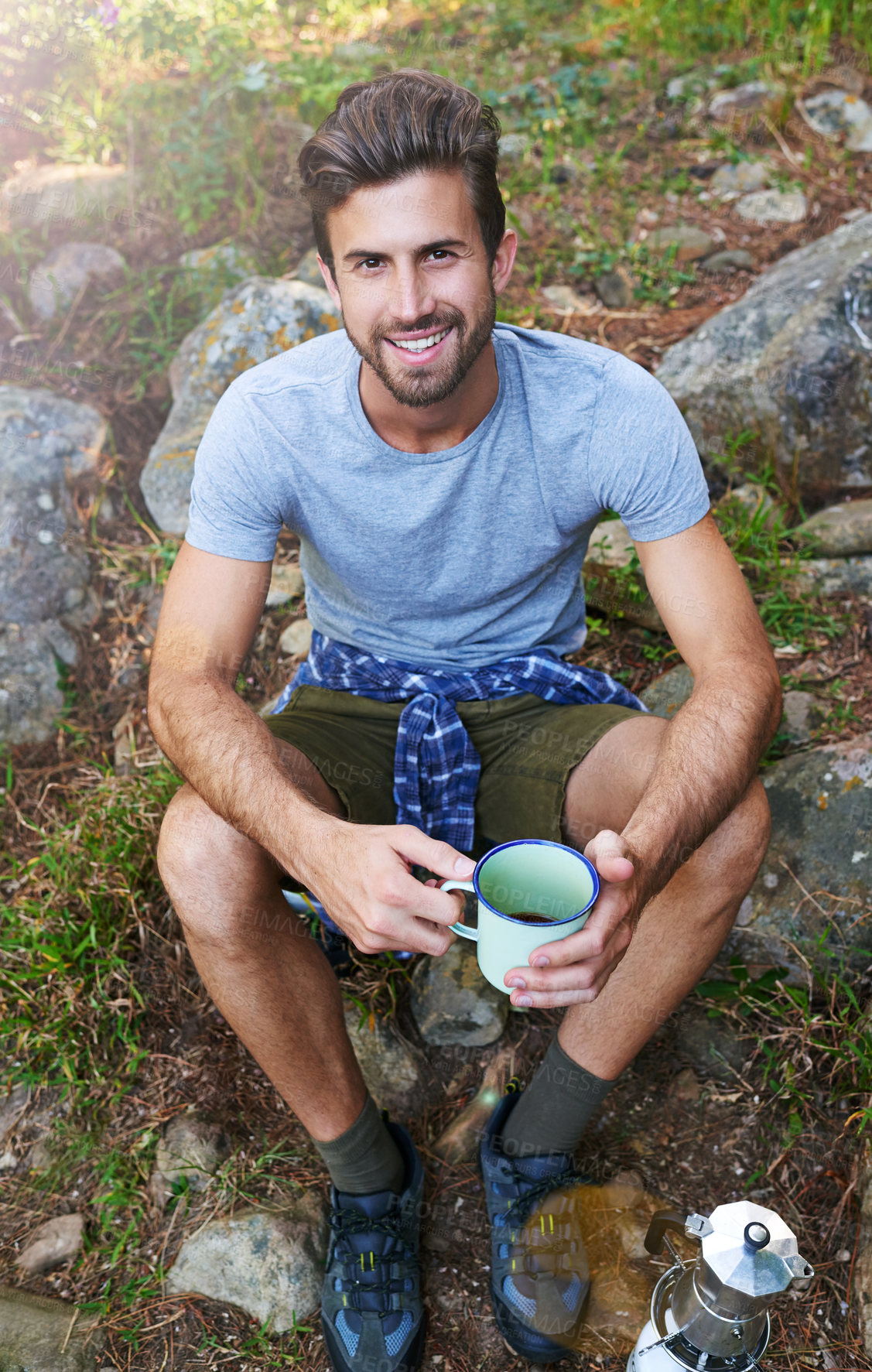 Buy stock photo Shot of a young man drinking a coffee while out on a hike