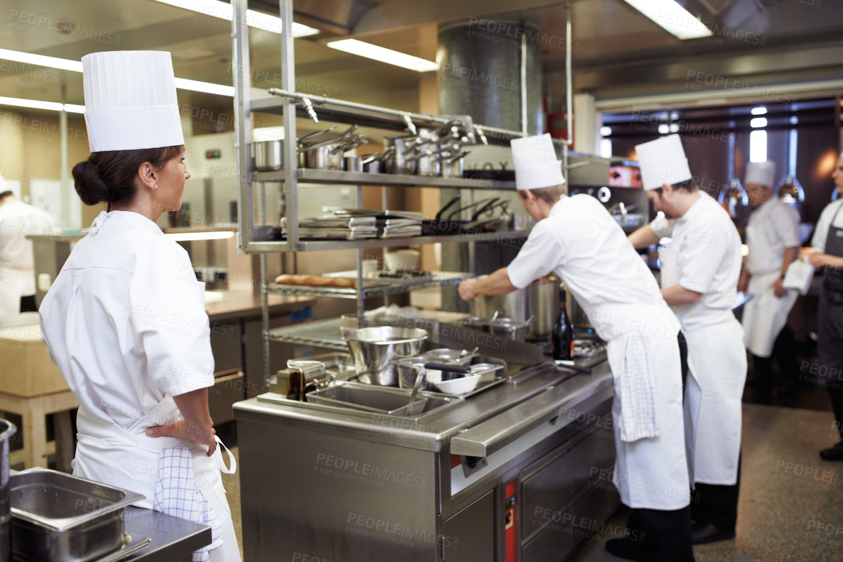 Buy stock photo Chef, staff and cooking professional in kitchen for evaluation of culinary education, training and performance management. Woman, students and supervision for feedback or guidance and learning skill.