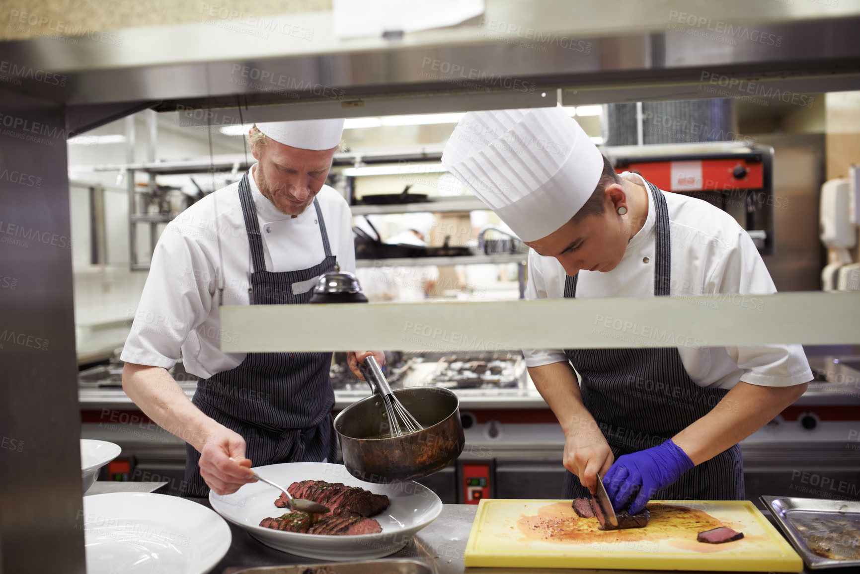 Buy stock photo Chefs, sausage and men cutting in kitchen of restaurant for dinner, lunch or supper with hospitality. Career, catering and culinary staff with knife chop steak meat for fine dining in gourmet cafe.