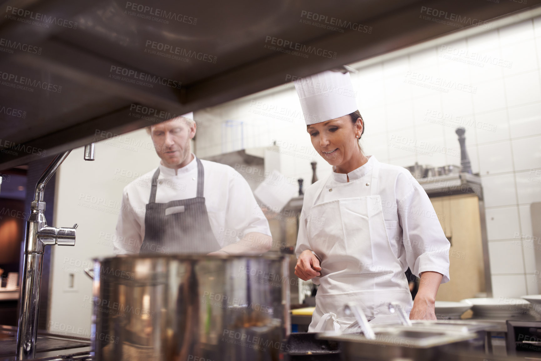 Buy stock photo Chef, teamwork and cooking in professional kitchen at stove top or fine dining cuisine, hospitality or service. Man, woman an hat as restaurant career or food preparation or dinner rush, meal or help