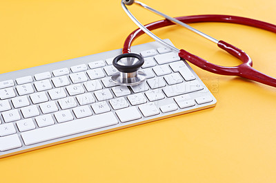 Buy stock photo Concept shot of a keyboard and stethoscope on a yellow background