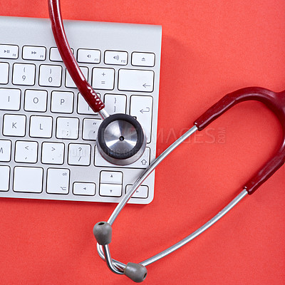 Buy stock photo Concept shot of a keyboard and stethoscope on a red background