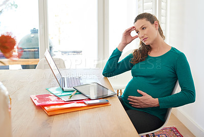Buy stock photo Shot of a pregnant woman looking thoughtful while sitting at her computer at home