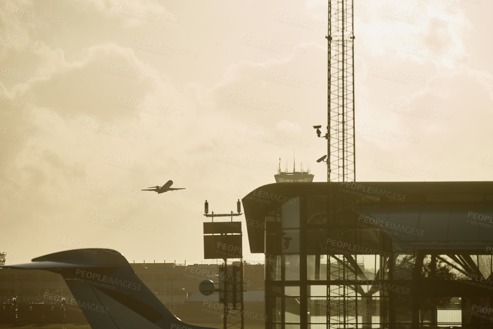 Buy stock photo An airplane flying over an airport building near an air traffic control tower. A passenger plane departure outside in cloudy sky. An airplane taking off over a bright sky on international flight