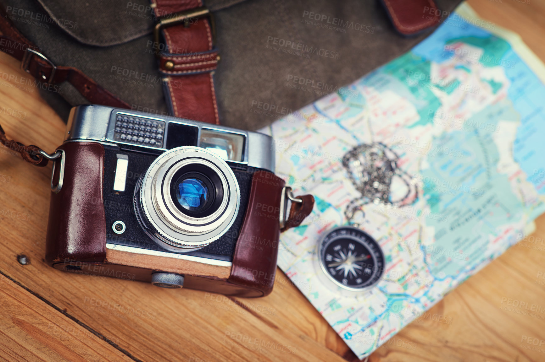 Buy stock photo Shot of a camera, map, compass and bag on a wooden table