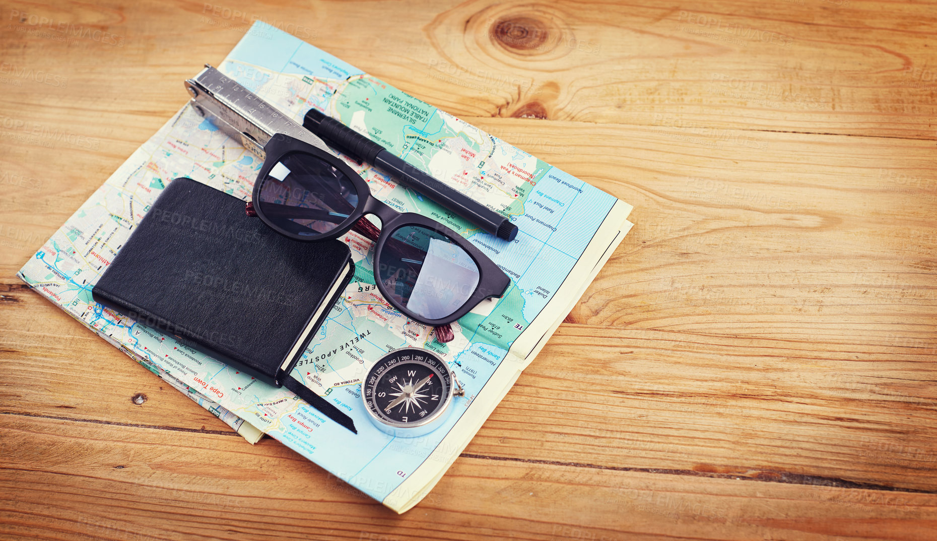 Buy stock photo High angle shot of sunglasses, a notebook, a compass and utility tool on a map