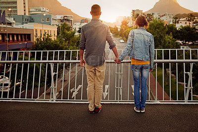 Buy stock photo Rearview shot of a couple standing together on a city bridge and looking at the view