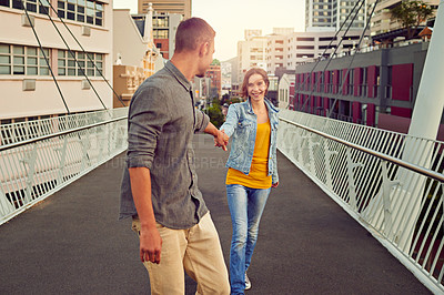 Buy stock photo Shot of a happy young couple enjoying a romantic walk together in the city