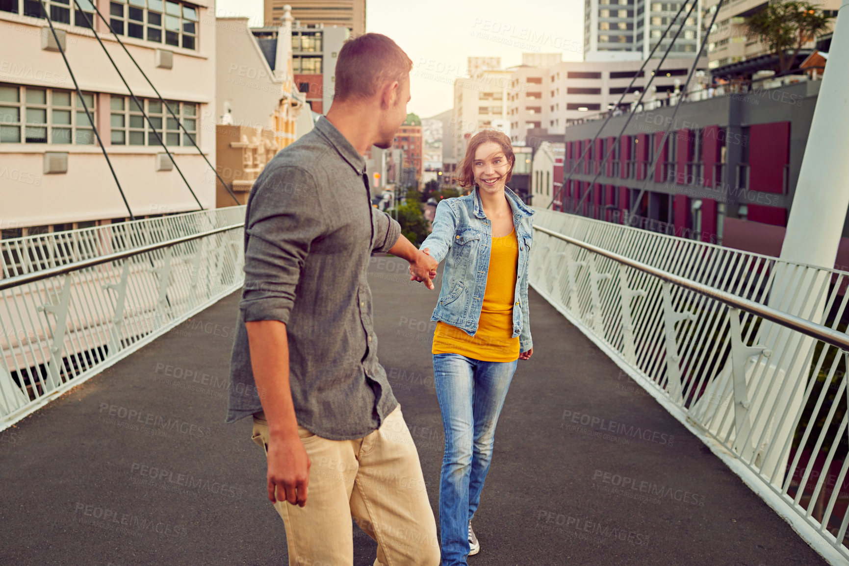 Buy stock photo Shot of a happy young couple enjoying a romantic walk together in the city