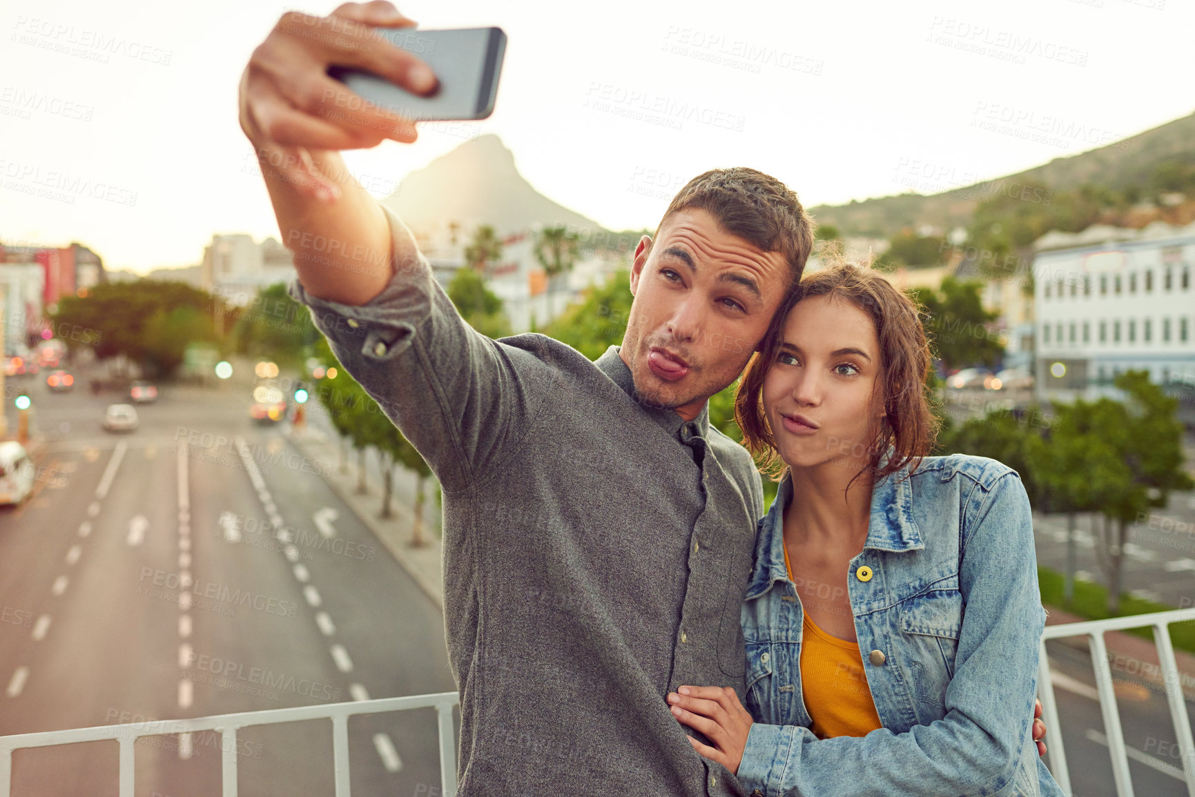 Buy stock photo Shot of a happy young couple taking a selfie together in the city