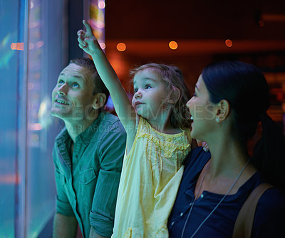 Buy stock photo Family, aquarium and child pointing at fish for learning, curiosity or knowledge, bonding or care. Mother, fishtank and happy kid with father watching marine animals swim underwater in oceanarium.