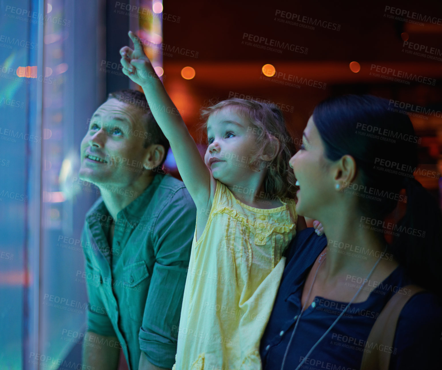 Buy stock photo Family, aquarium and child pointing at fish for learning, curiosity or knowledge, bonding or care. Mother, fishtank and happy kid with father watching marine animals swim underwater in oceanarium.