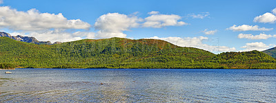 Buy stock photo A hill behind a lake on summer day with clouds in the sky. Beautiful landscape view with greenery in nature. Mountain pastures in the background of a lake. Lush hill with pasture near water outdoors