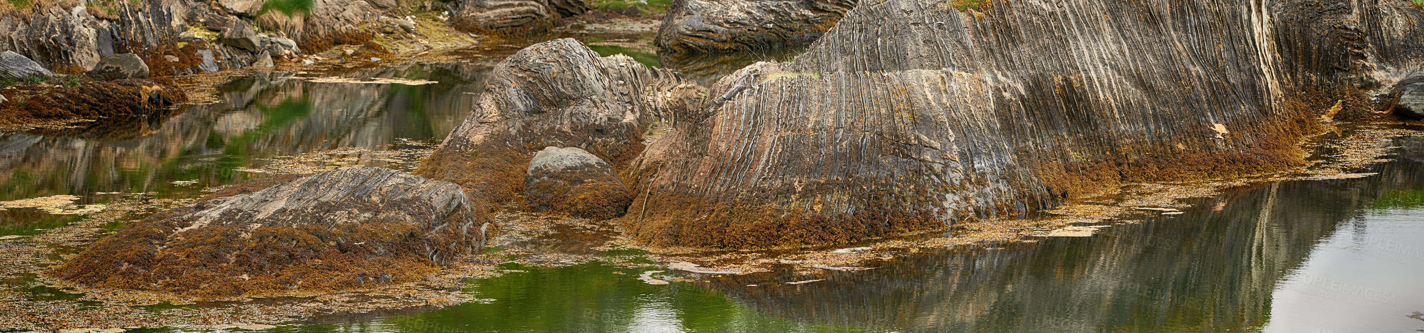 Buy stock photo Landscape panorama of a hill and lake in arctic circle in Norway. Scenic view of water washing around boulders and rocks in remote lagoon area. Traveling abroad and overseas for holiday and vacation