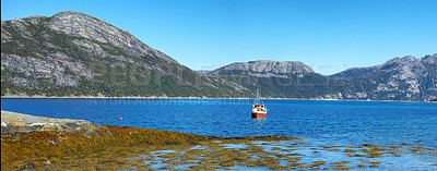 Buy stock photo Wide angle landscape of a remote fishing lake near mountains. Stone hills by the nordic seaside with a bright blue sky. Calm water for a peaceful environment on a holiday in scenic Nordland nature