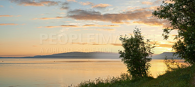 Buy stock photo Copyspace and scenic landscape of  a lake or river and mountains north of polar and arctic circle in Norway during sunset. Trees and calm sea in remote area with clouds. Travel to nature for holiday