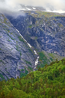 Buy stock photo Morning, waterfall and mountains with forest in winter for travel, climbing and hiking. Landscape, nature and view of green environment, clouds and Norway countryside for calm adventure on rocks