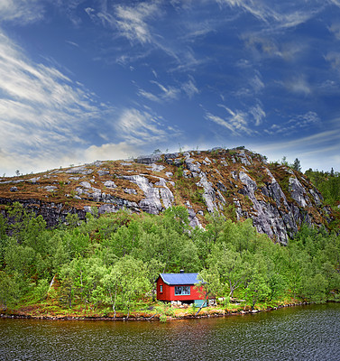 Buy stock photo Landscape, cabin and mountains in forest, sky or clouds by house by water, fjord and countryside. Building, home and outdoor by hill, trees or off the grid for sustainability in environment in Norway