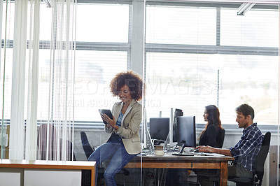 Buy stock photo Cropped shot of a beautiful young businesswoman using her tablet in the office
