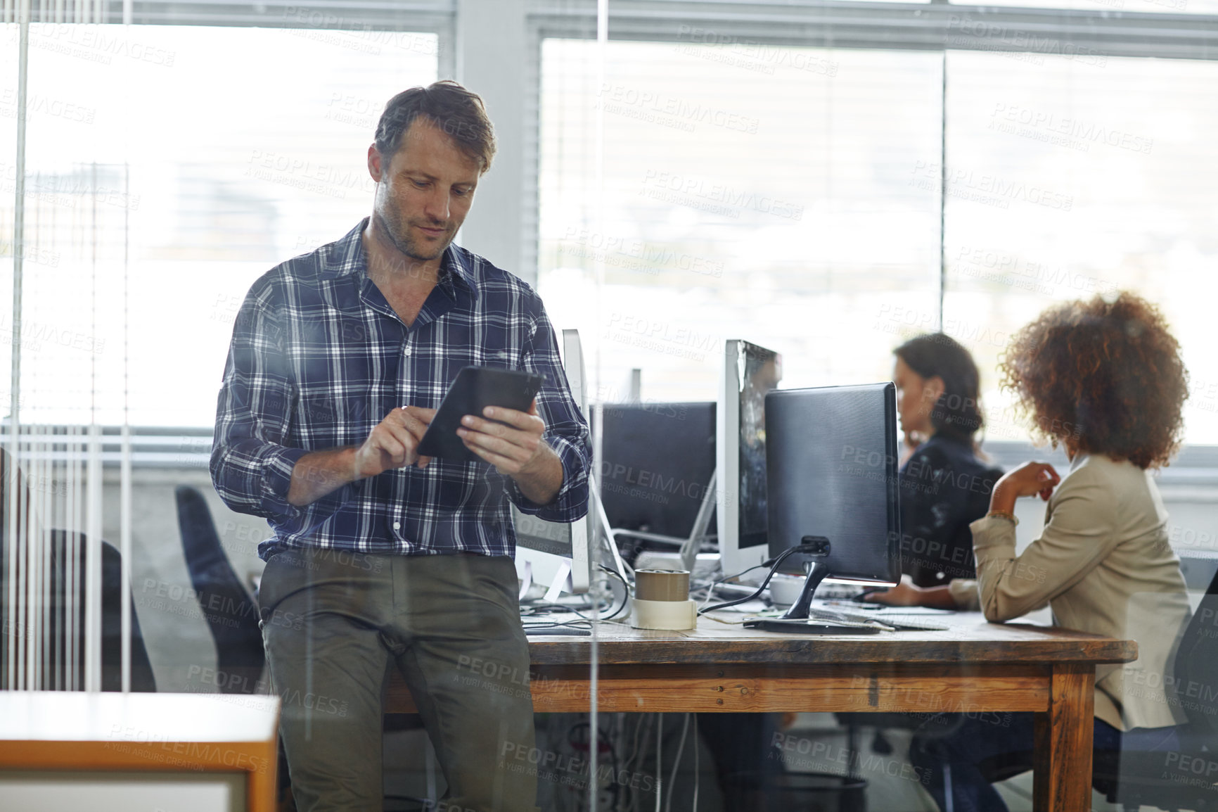 Buy stock photo Cropped shot of a handsome businessman using his tablet in the office