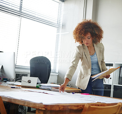 Buy stock photo Cropped shot of a beautiful young businesswoman looking over some documents in her office