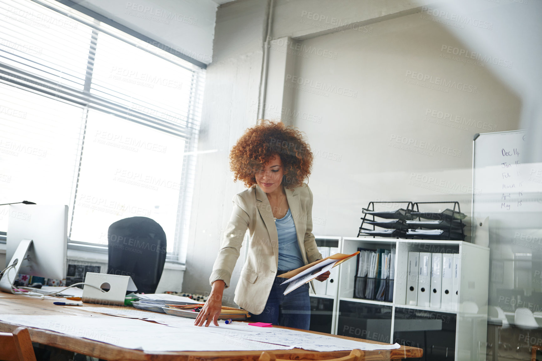 Buy stock photo Cropped shot of a beautiful young businesswoman looking over some documents in her office