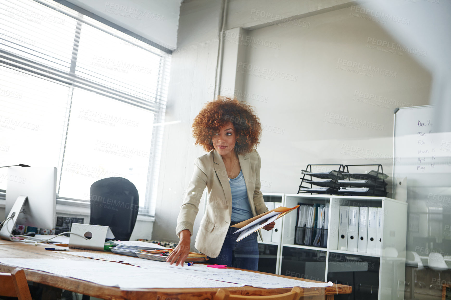 Buy stock photo Cropped shot of a beautiful young businesswoman looking over some documents in her office