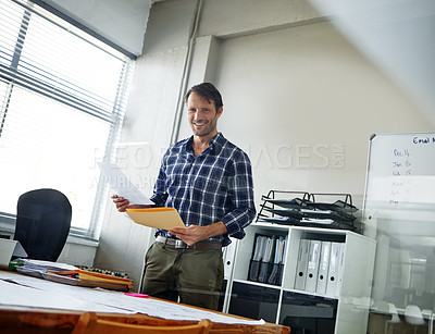 Buy stock photo Cropped shot of a handsome businessman looking over some documents in his office