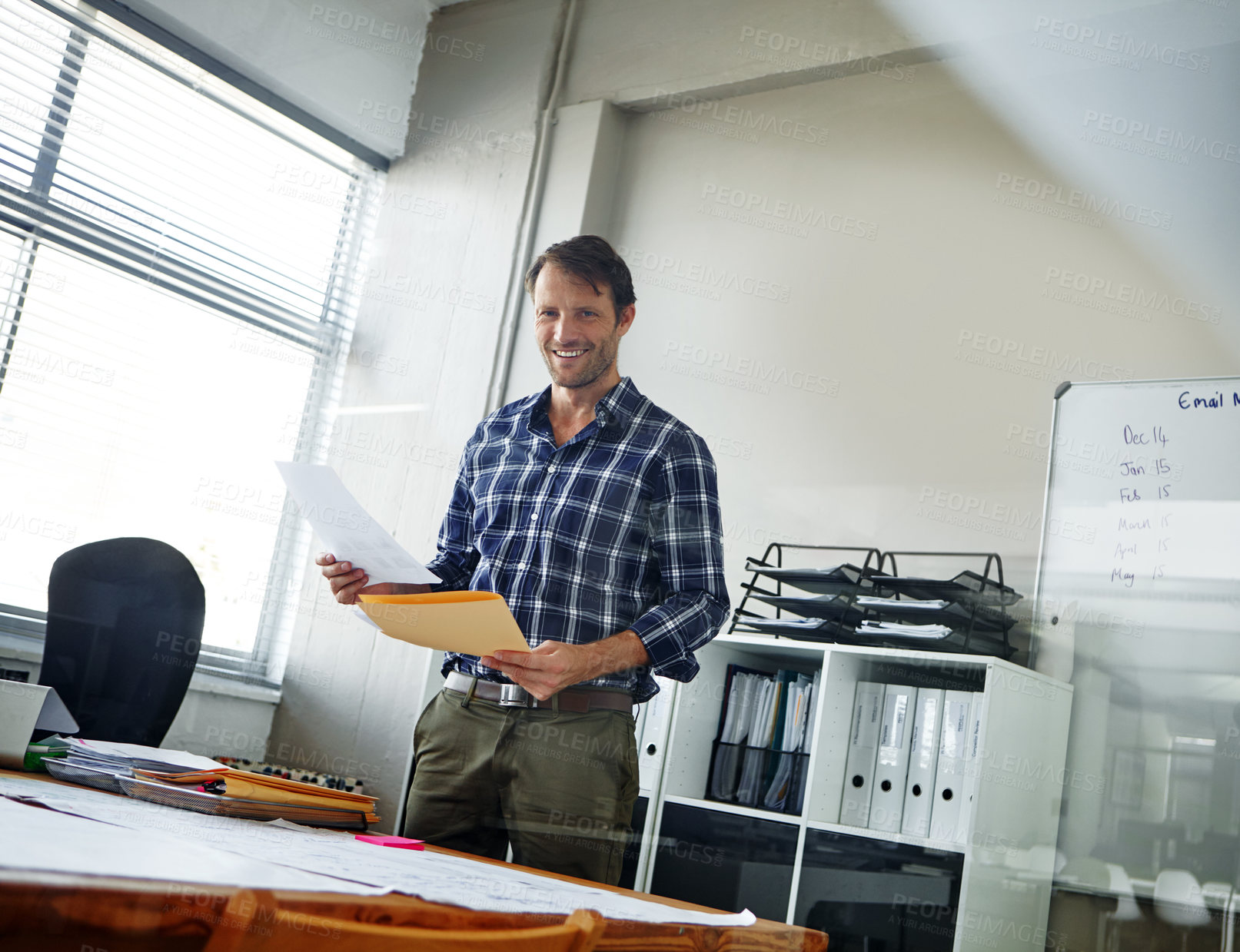 Buy stock photo Cropped shot of a handsome businessman looking over some documents in his office