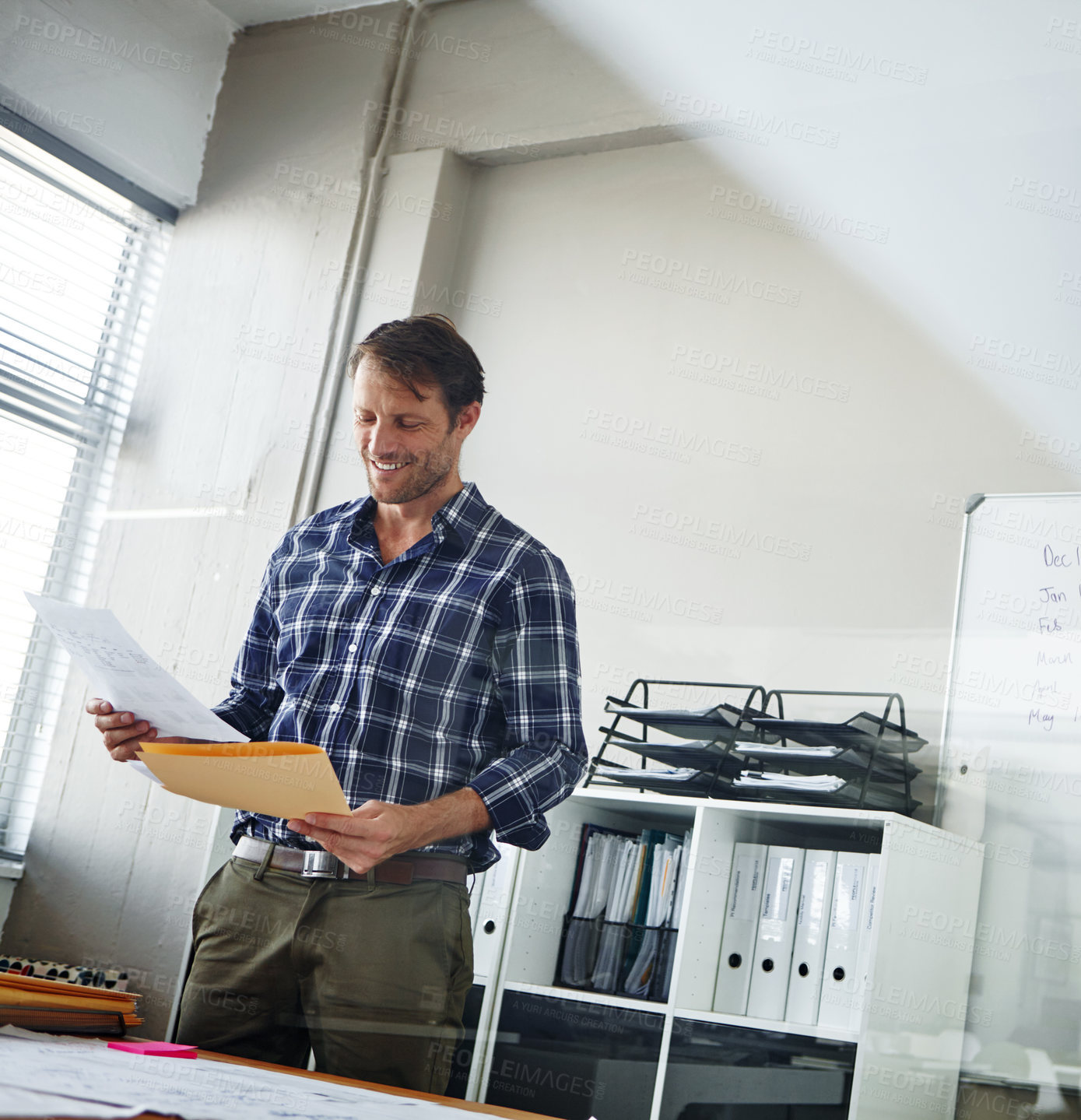 Buy stock photo Cropped shot of a handsome businessman looking over some documents in his office