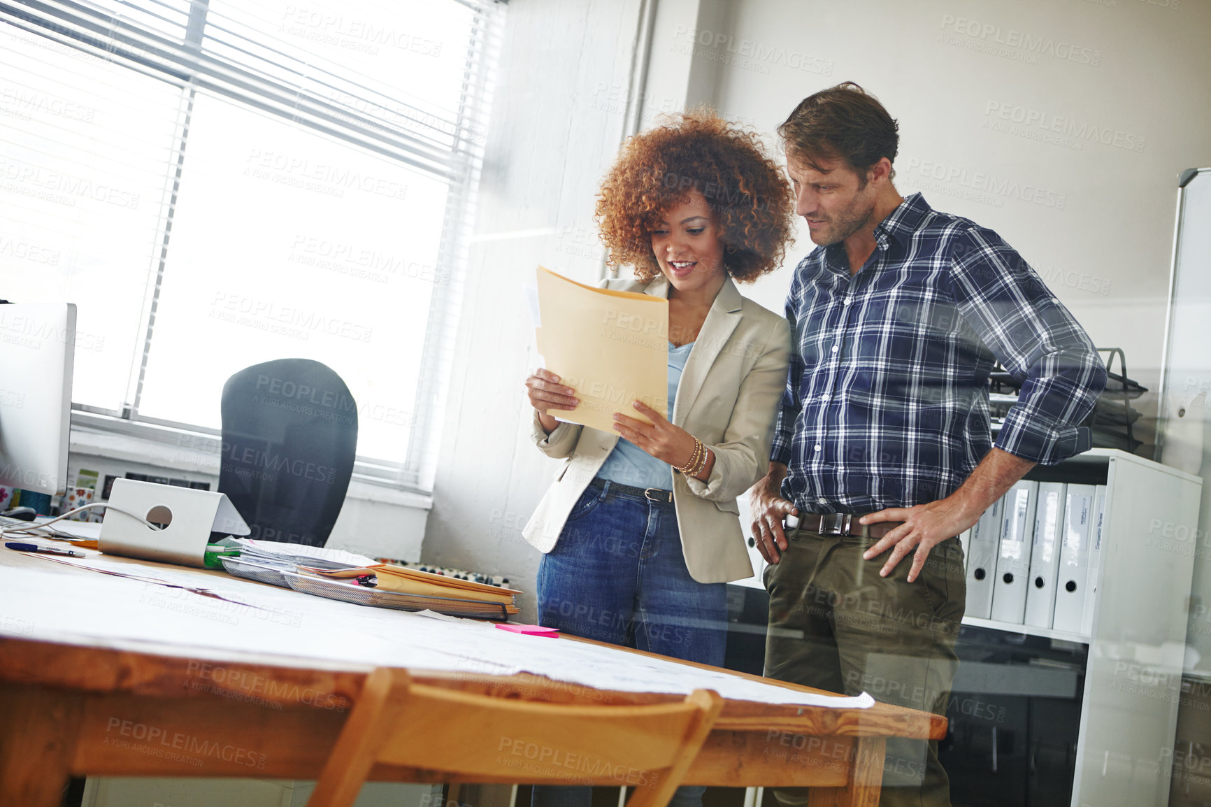 Buy stock photo Cropped shot of two coworkers looking over some documents in the office