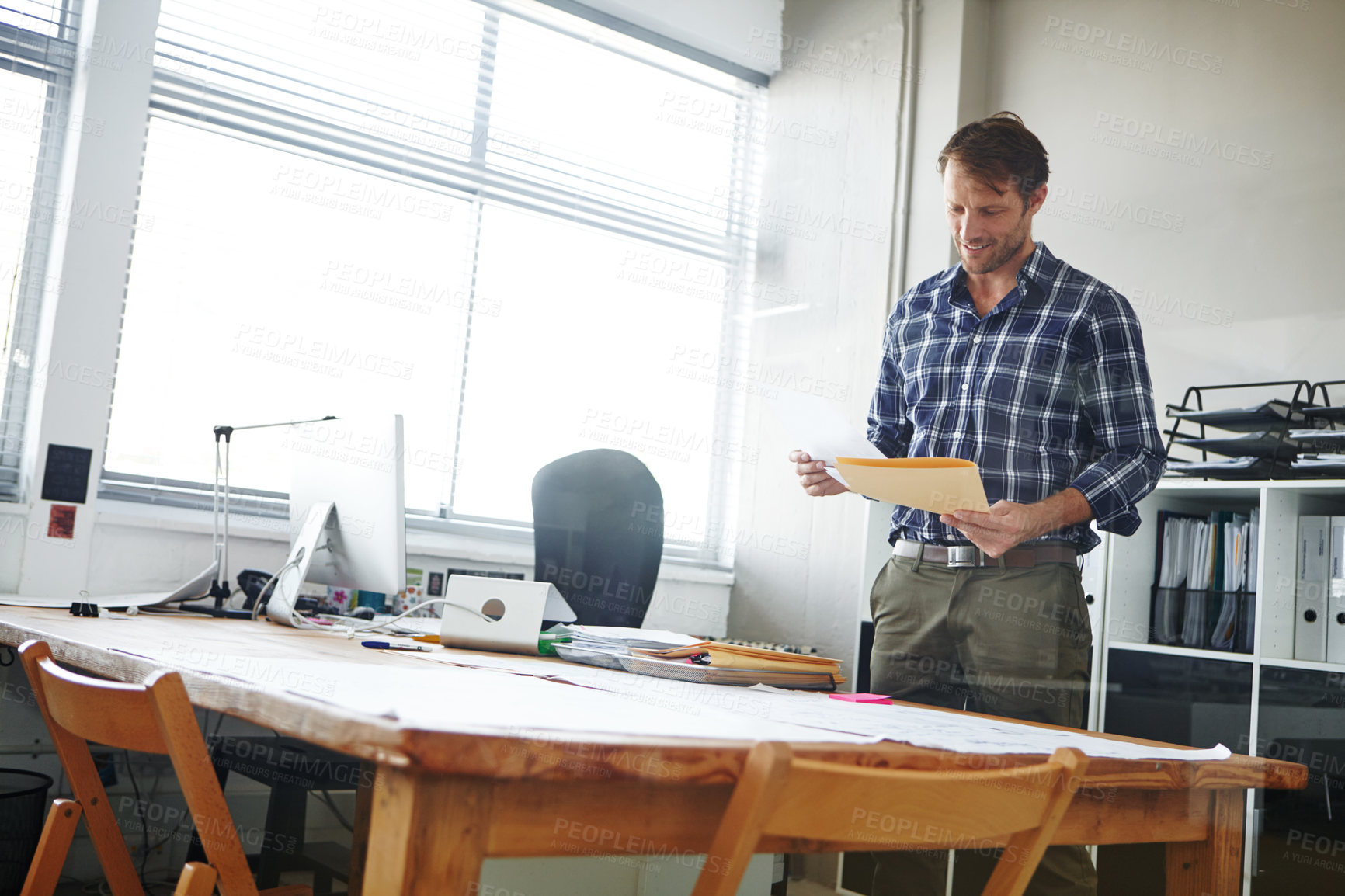 Buy stock photo Cropped shot of a handsome businessman looking over some documents in his office