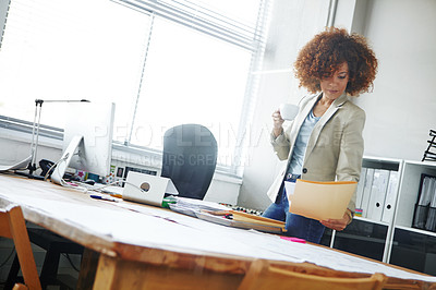 Buy stock photo Cropped shot of a beautoful young businesswoman looking over some documents in her office