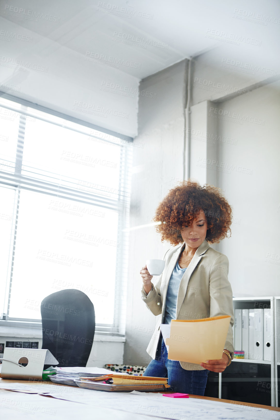 Buy stock photo Cropped shot of a beautoful young businesswoman looking over some documents in her office