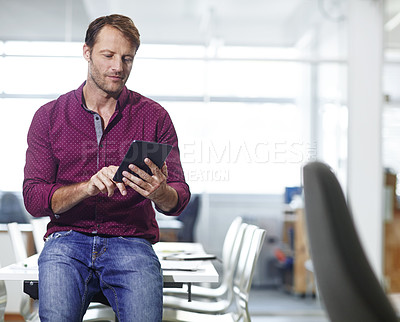 Buy stock photo Cropped shot of a handsome businessman using his tablet in the office