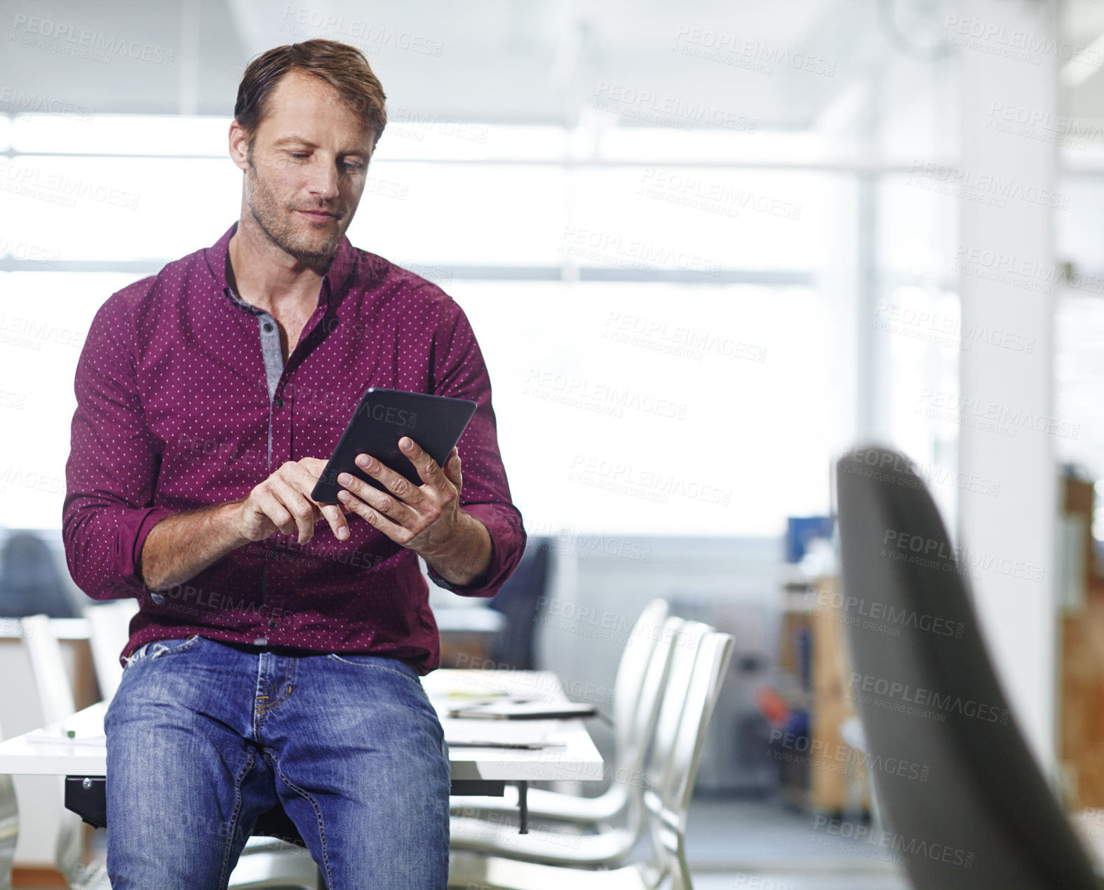 Buy stock photo Cropped shot of a handsome businessman using his tablet in the office