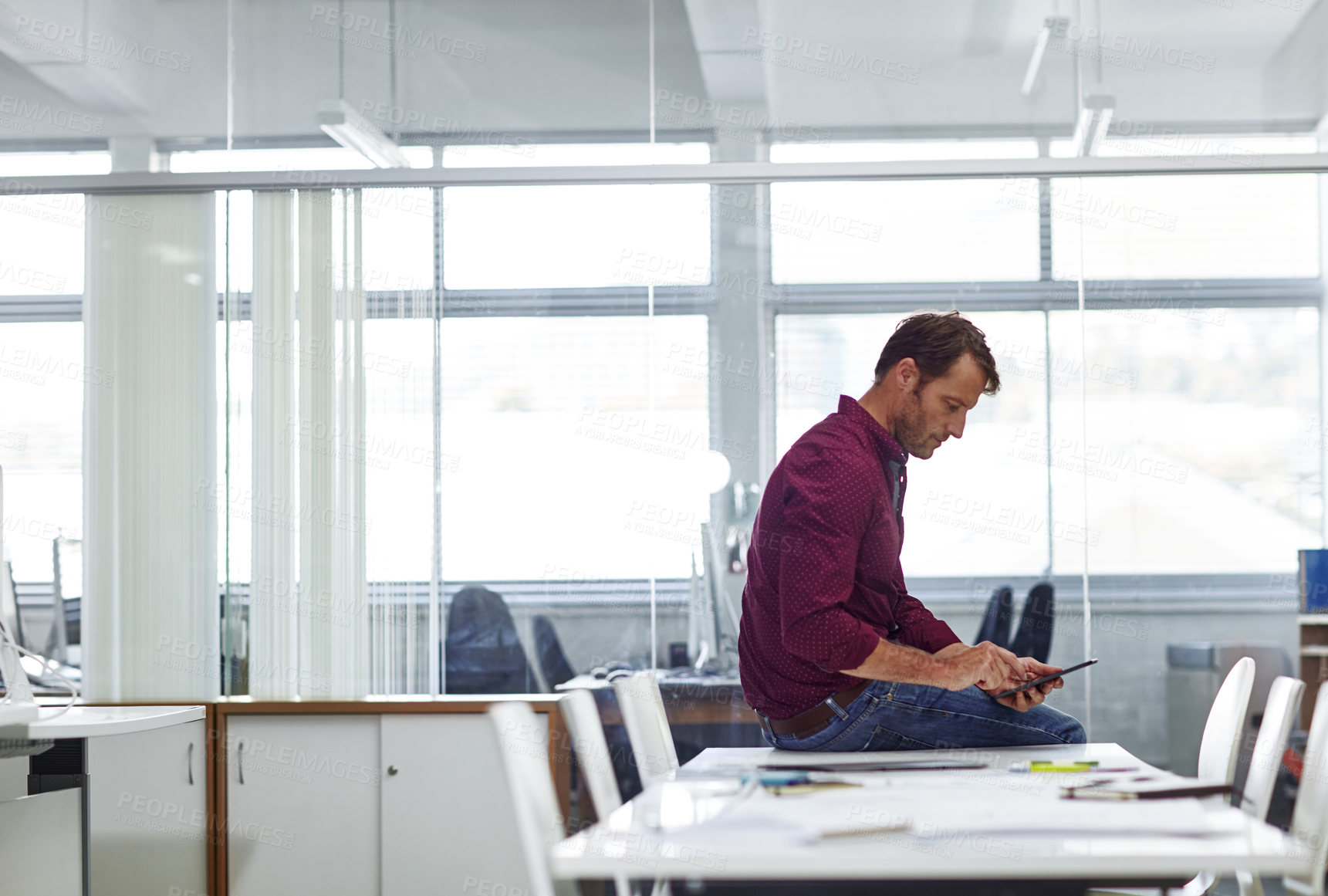 Buy stock photo Cropped shot of a handsome businessman using his tablet in the office