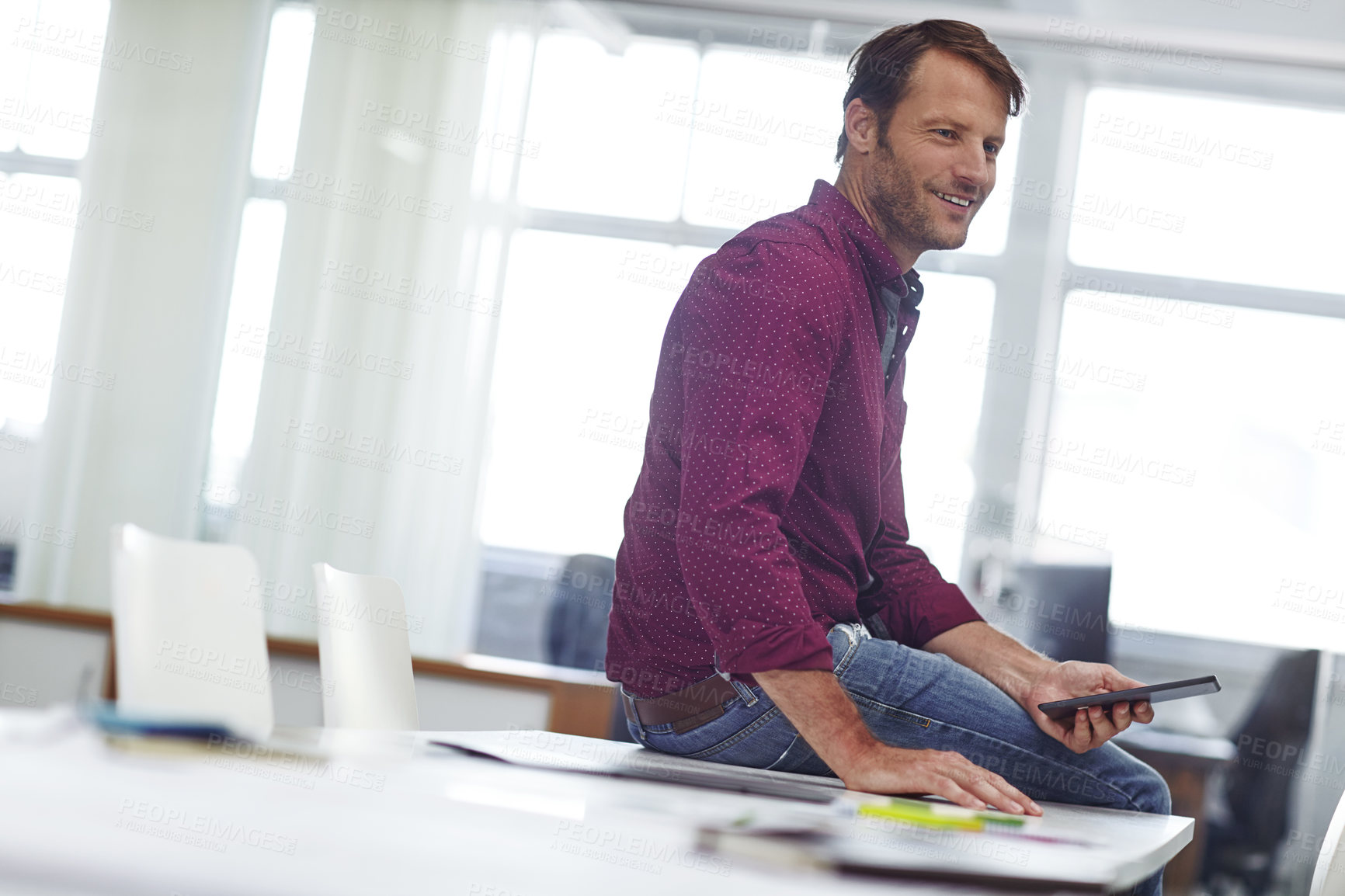 Buy stock photo Cropped shot of a handsome businessman using his tablet in the office