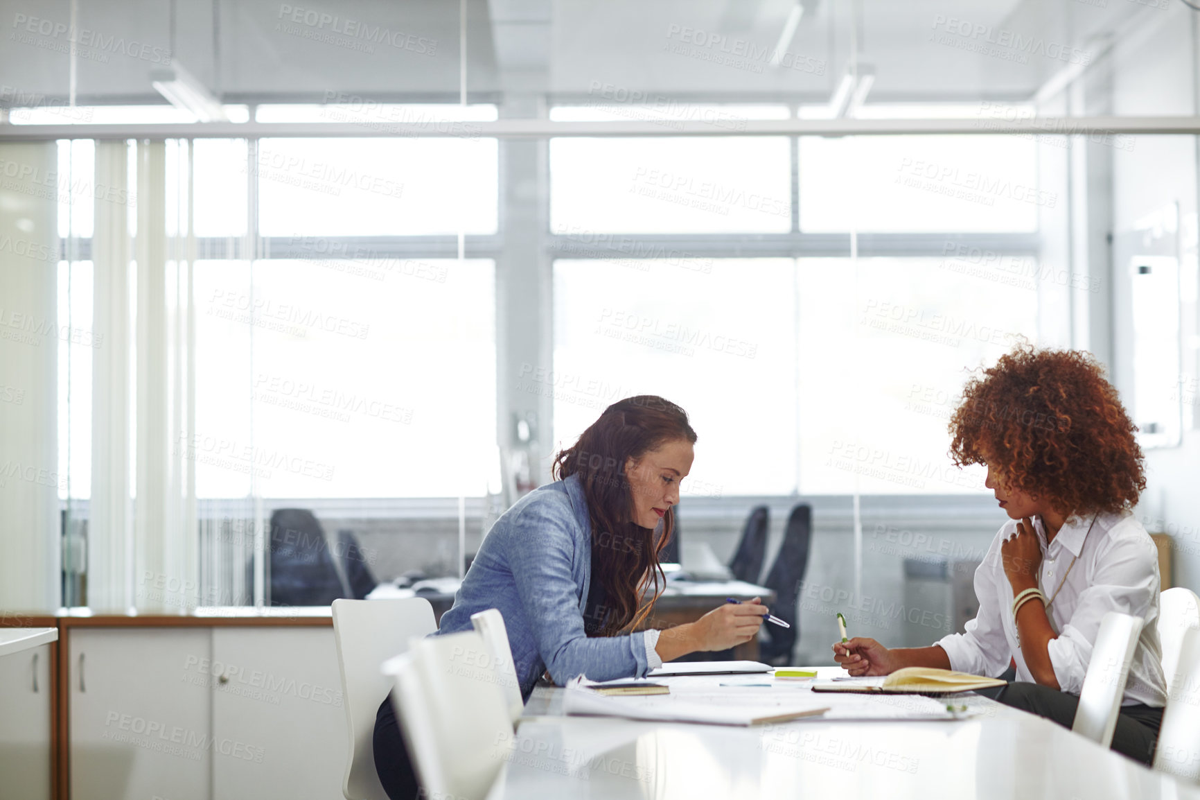 Buy stock photo Shot of two young female designers discussing work in the office