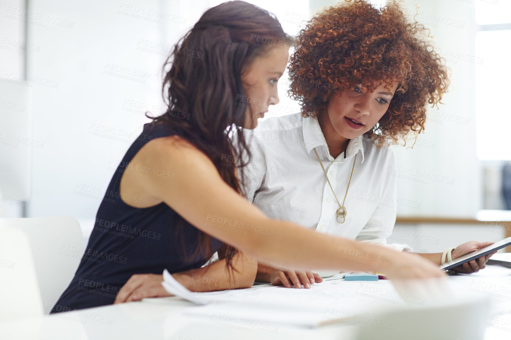 Buy stock photo Shot of two young female designers discussing work in the office