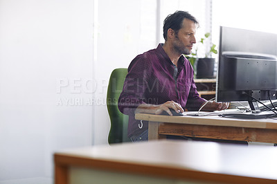 Buy stock photo Shot of a handsome man at work on his computer in the office